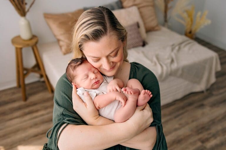 A heartwarming moment captured in this image reveals a mother's love and warmth. The devoted mom cradles her baby in her arms, their cheeks gently pressed together in an intimate snuggle. Their bond radiates through their shared embrace, conveying a profound sense of tenderness, comfort, and a deep connection between parent and child