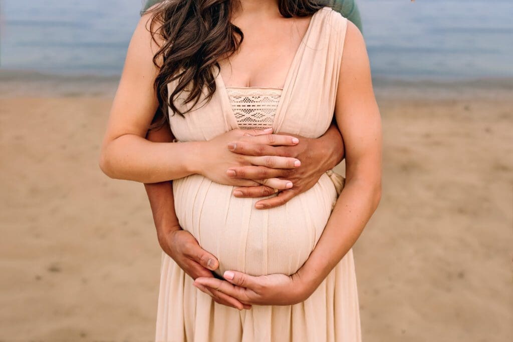 An endearing moment as both mom and dad's hands cradle the pregnant belly, symbolizing the loving bond with their unborn child during this special maternity photoshoot.