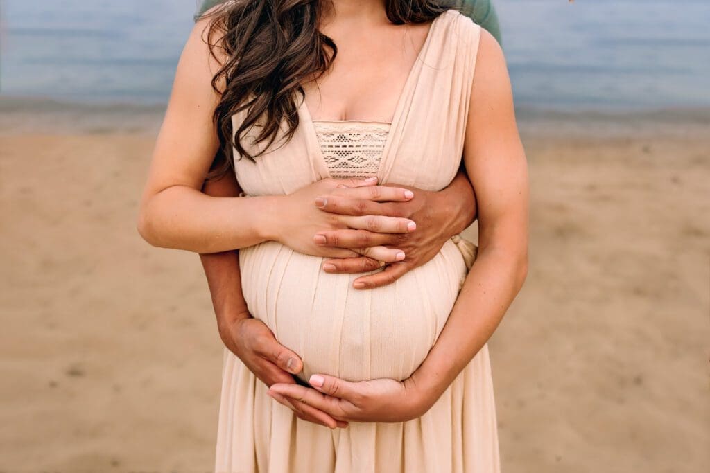 Crofton-Maternity-Photoshoot-12 An endearing moment as both mom and dad's hands cradle the pregnant belly, symbolizing the loving bond with their unborn child during this special maternity photoshoot.