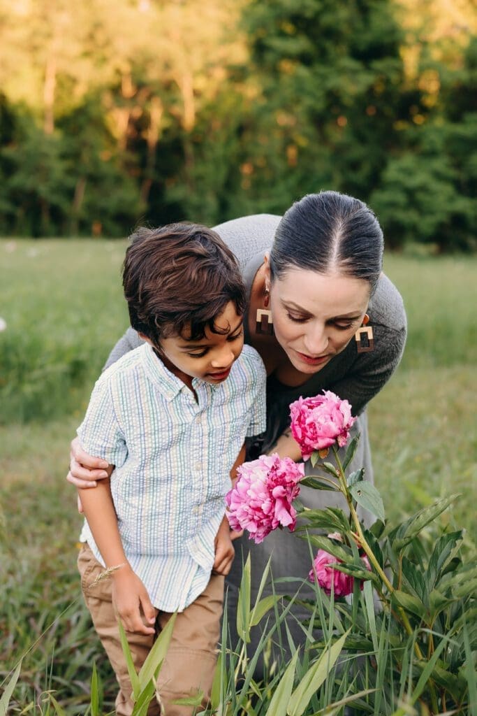 Family joy captured in Schwartz Peony Garden: a heartwarming scene of mom, dad, and their young son enjoying a fun day at Seneca Creek State Park. Mom and son stop to smell the peonies.