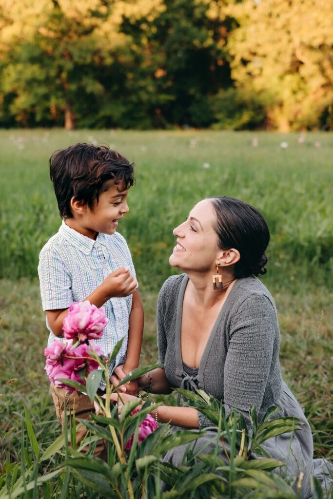 A family day out at Schwartz Peony Garden—enjoying playful moments, walks, and cozy snuggles amidst the picturesque scenery. Mom and son share a moment as they stop to smell the peonies.