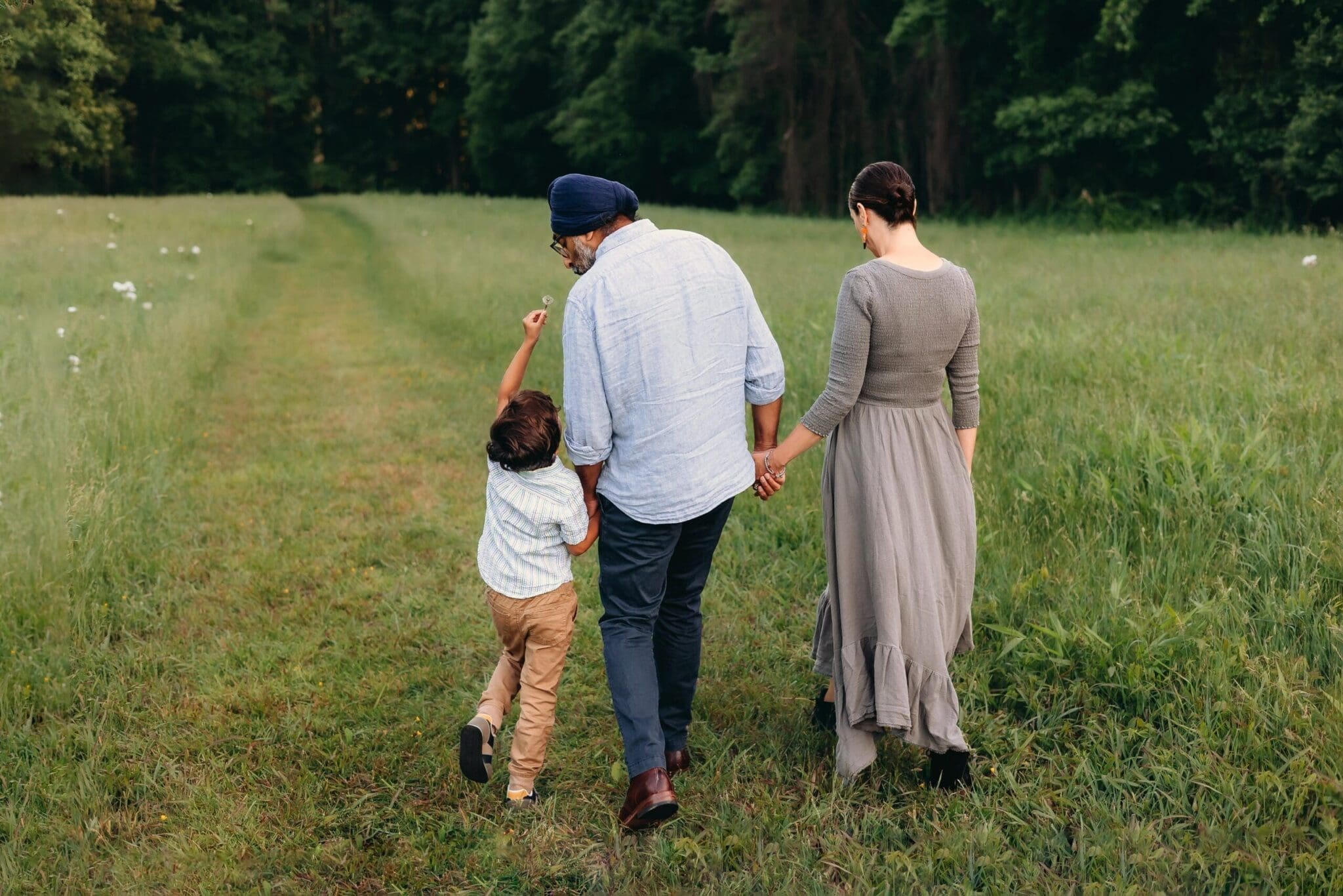 A beautiful day in Schwartz Peony Garden—mom, dad, and their little boy enjoy playful antics, warm snuggles, and delightful laughter at Seneca Creek State Park. Son holds a flower up for dad to smell as the family walks hand in hand.