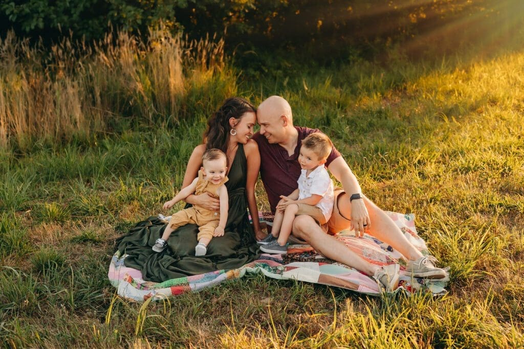 Mom and dad take in a moment of stillness as they rest their heads together during a sunset toddler photo session.