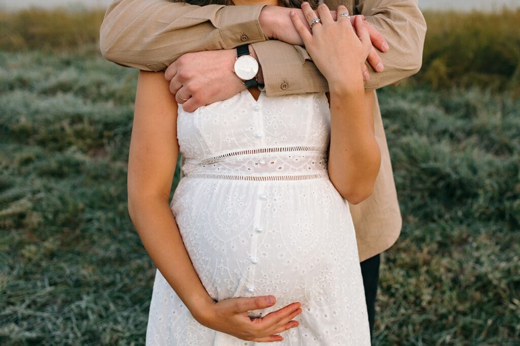 Hands lovingly placed on a pregnant belly in a close-up shot