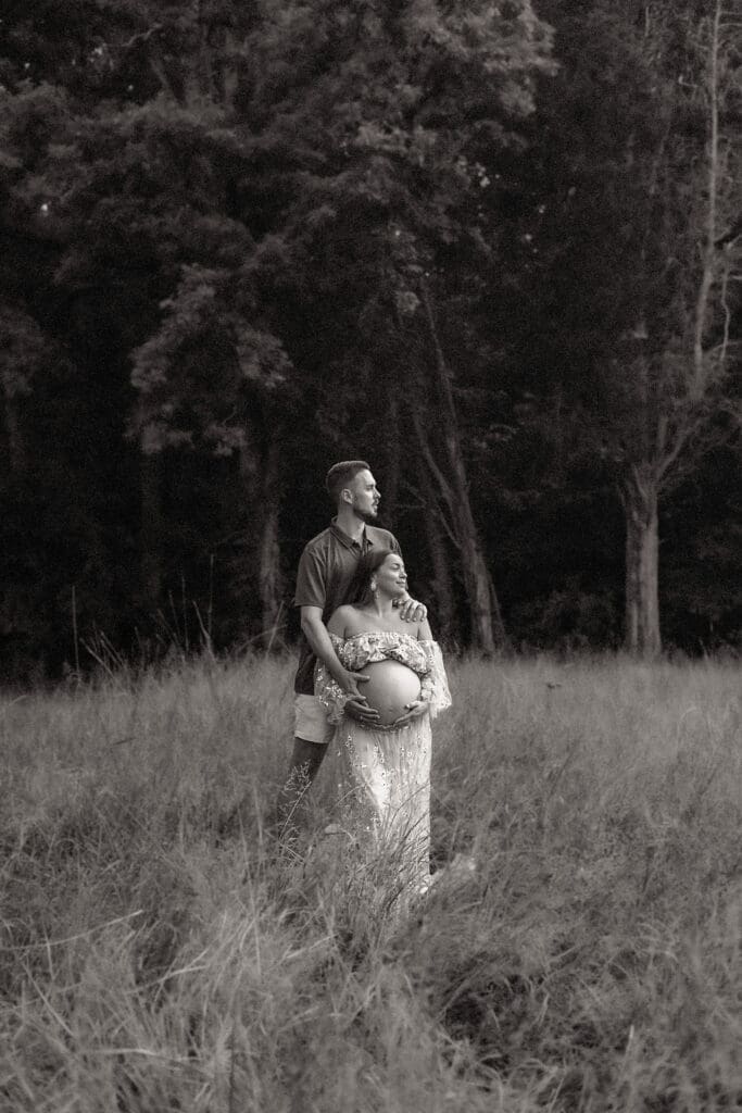 Couple sharing a quiet moment in a field during their maternity photoshoot.