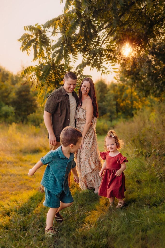 A playful family photography session at sunset in Bowie, Maryland, featuring two children running joyfully as their parents watch with smiles.