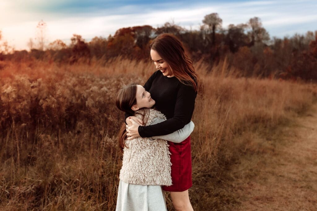 Tender moment of mother hugging her daughter at sunset during a lifestyle family photoshoot in Bowie, Maryland.