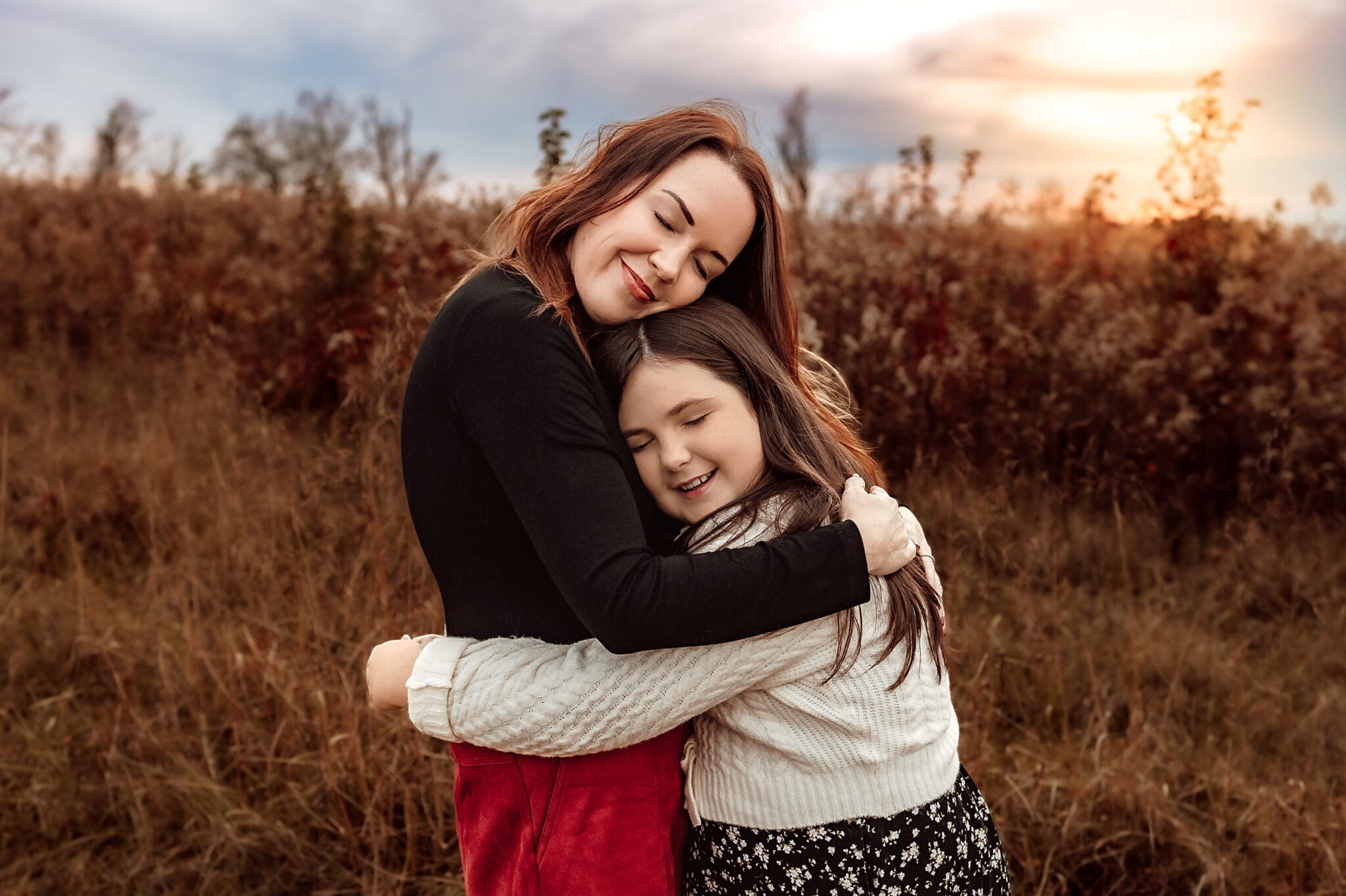 Close-up of mother kissing her daughter during a warm golden hour family photography session in Bowie, Maryland.