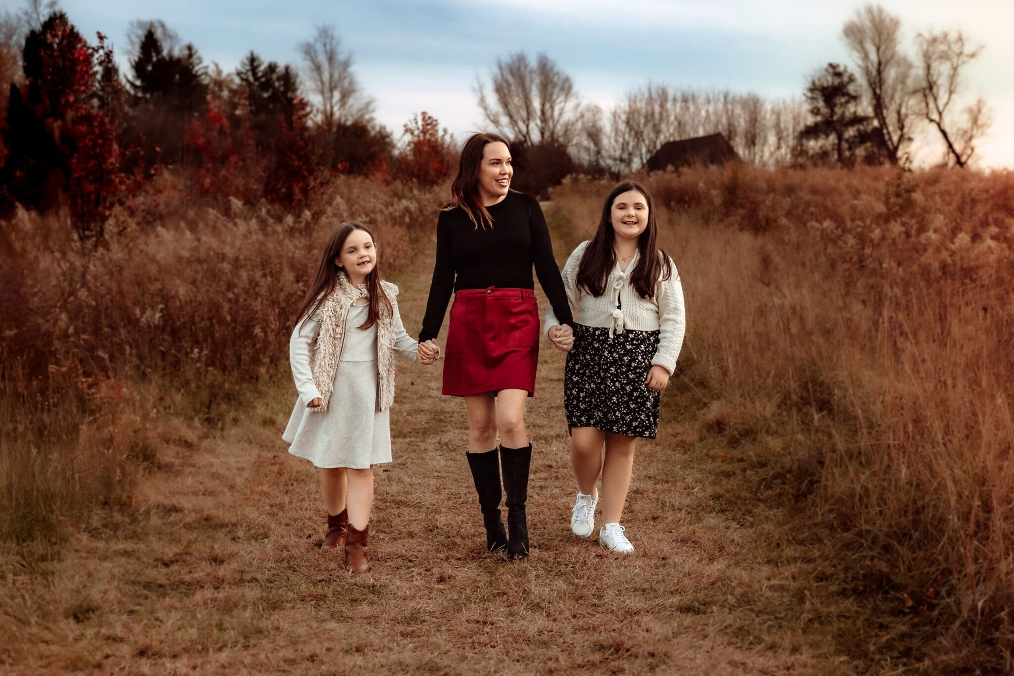 Mother walking hand-in-hand with her daughters during a candid outdoor family photography session in Bowie, Maryland.