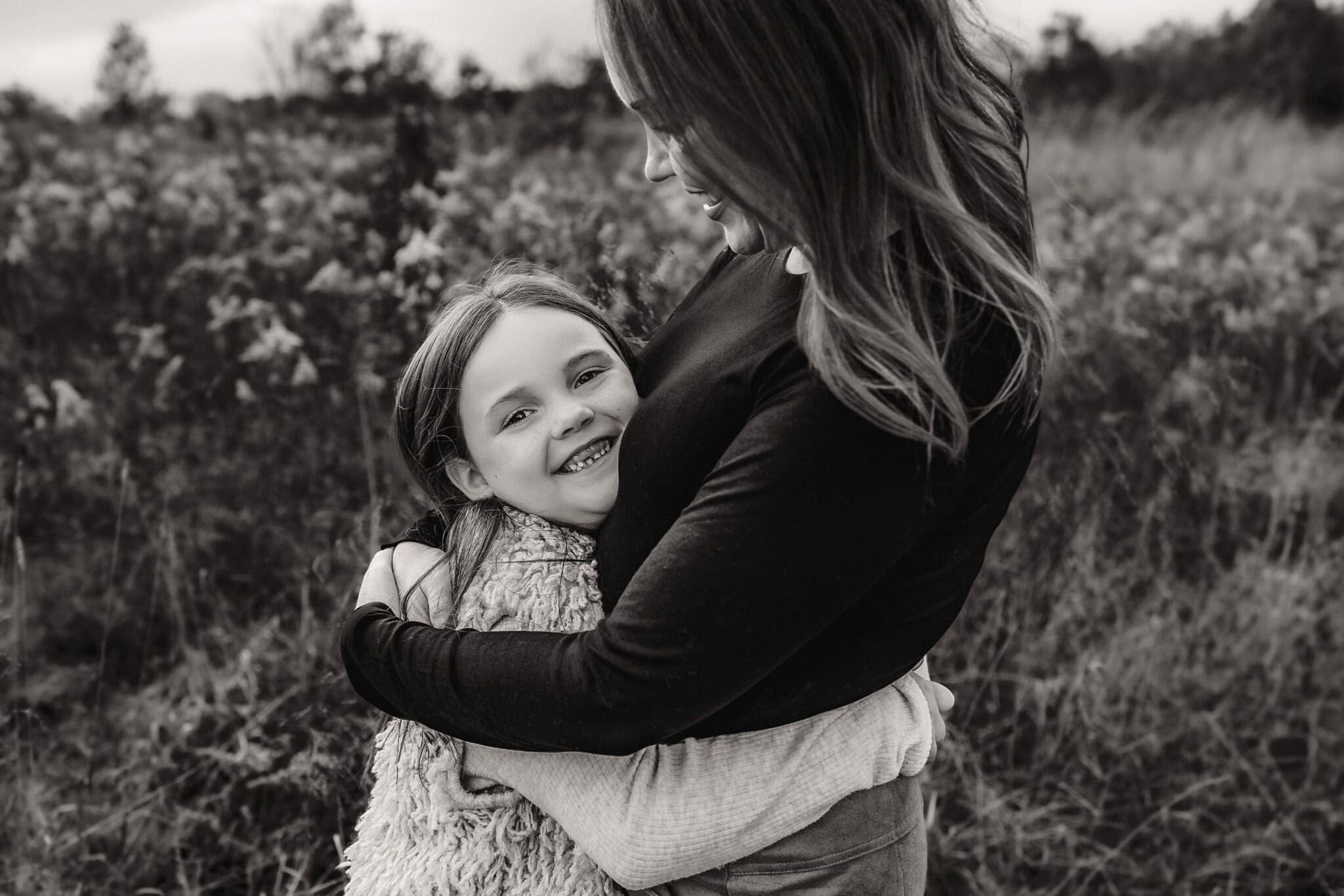 Black and white portrait of mother hugging her daughter during an emotional outdoor family session in Bowie, Maryland.