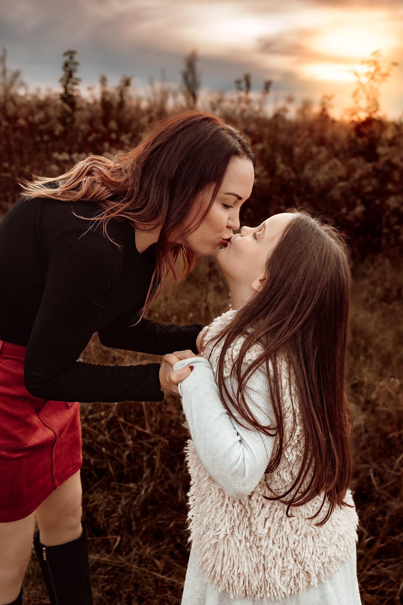 Close-up of mother kissing her daughter during a warm golden hour family photography session in Bowie, Maryland.
