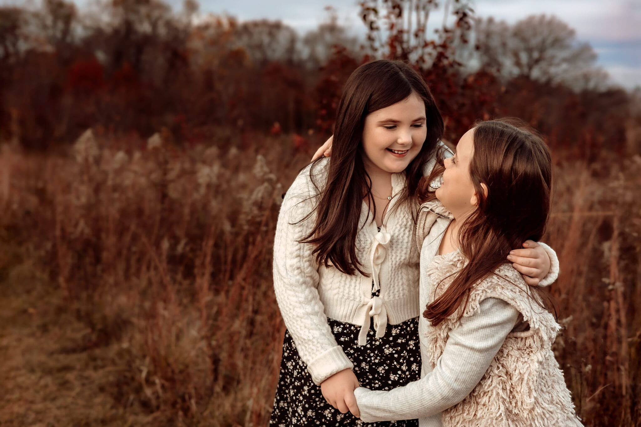 Two sisters embrace during golden hour family photos with a Bowie, Maryland family photographer.