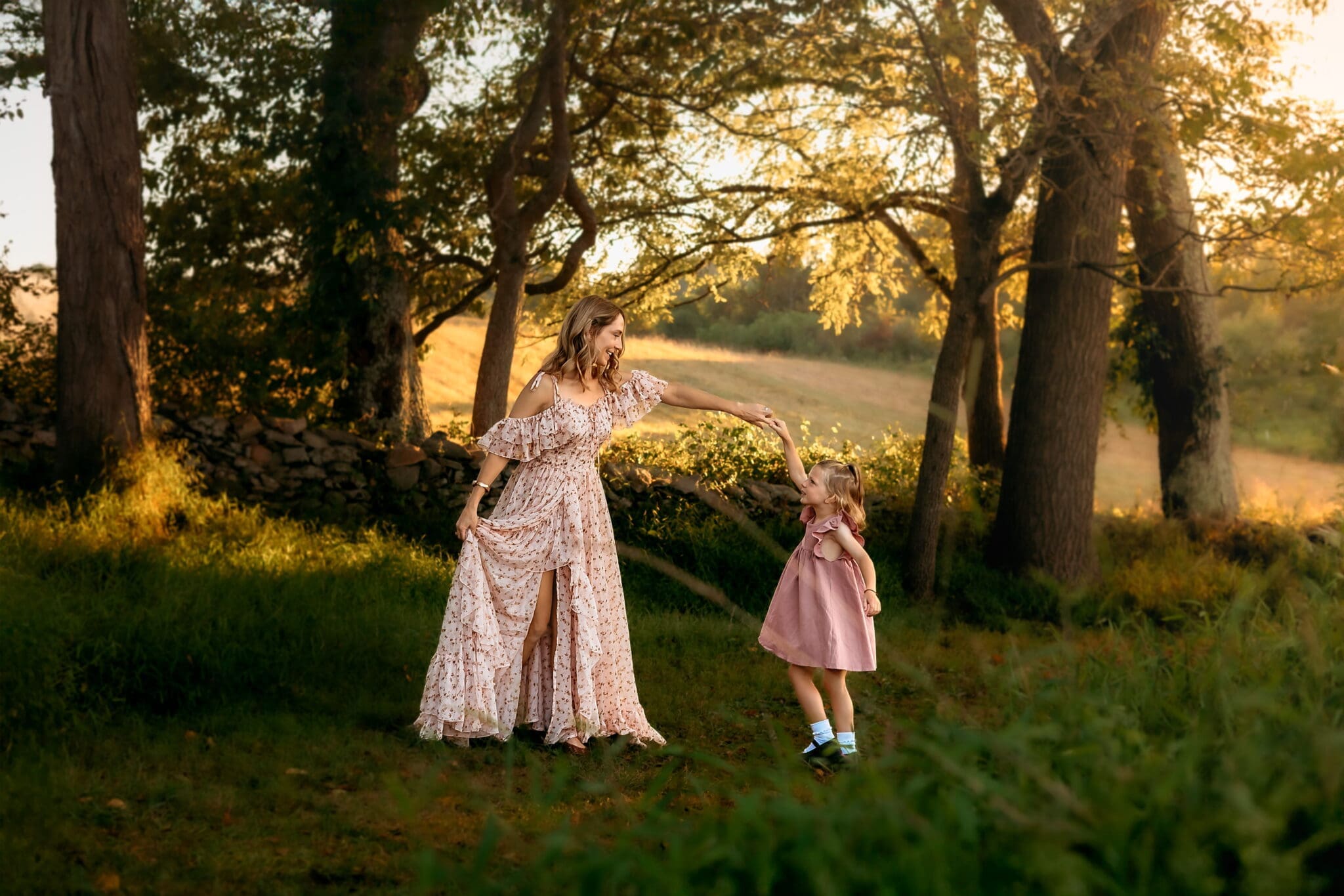 Mother dances with daughter on a wooded path in Maryland, mother in a floral dress