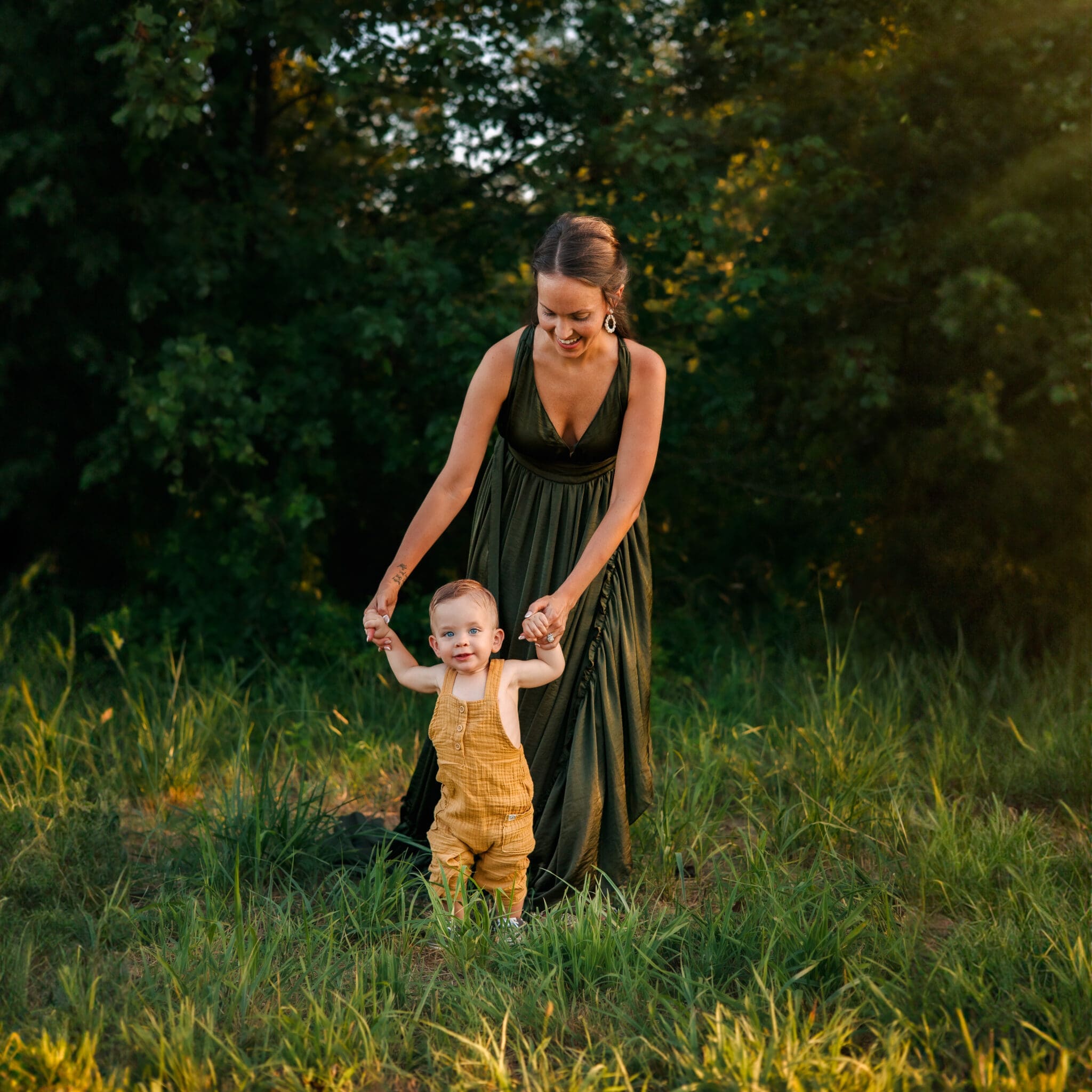 Mother and toddler walking through a green field in olive and mustard tones