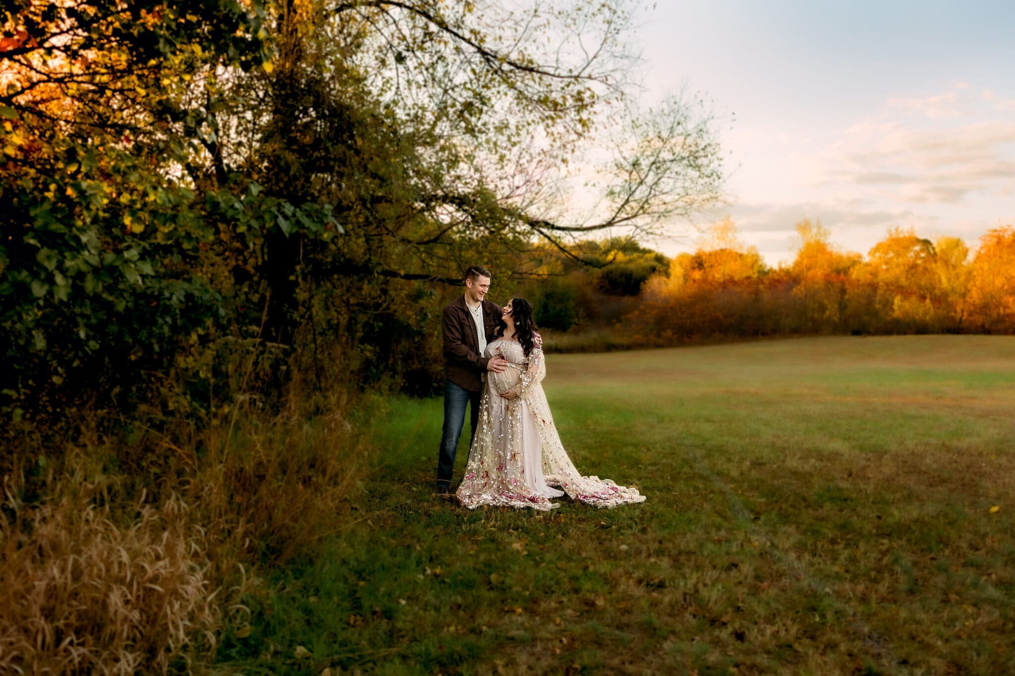 Expectant couple in a golden field with dramatic backlit sunset light
